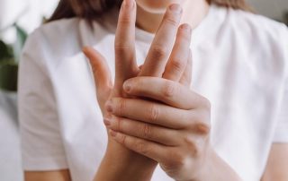 Parmak uyuşması sorunu yaşayan bir kadın sol eli ile uyuşan sağ elini tutuyor. Peki parmak uyuşması neden olur?